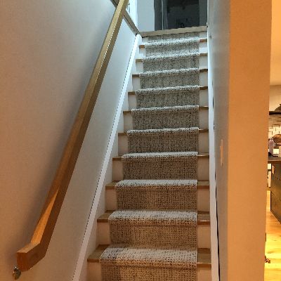 Light wood staircase with textured neutral runner and white risers.